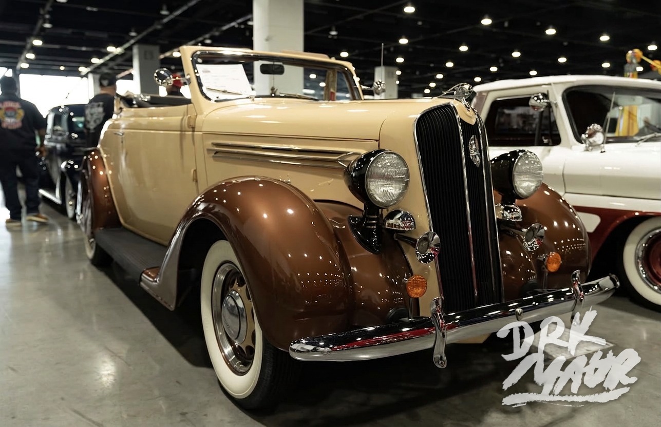 Two-tone cream and brown vintage Plymouth convertible on polished concrete at an indoor car show