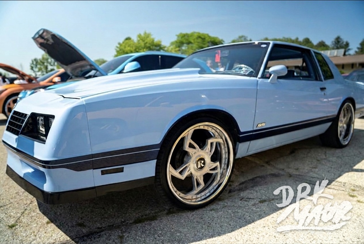 Powder blue Chevrolet Monte Carlo SS on gold and chrome wheels parked at an outdoor car show