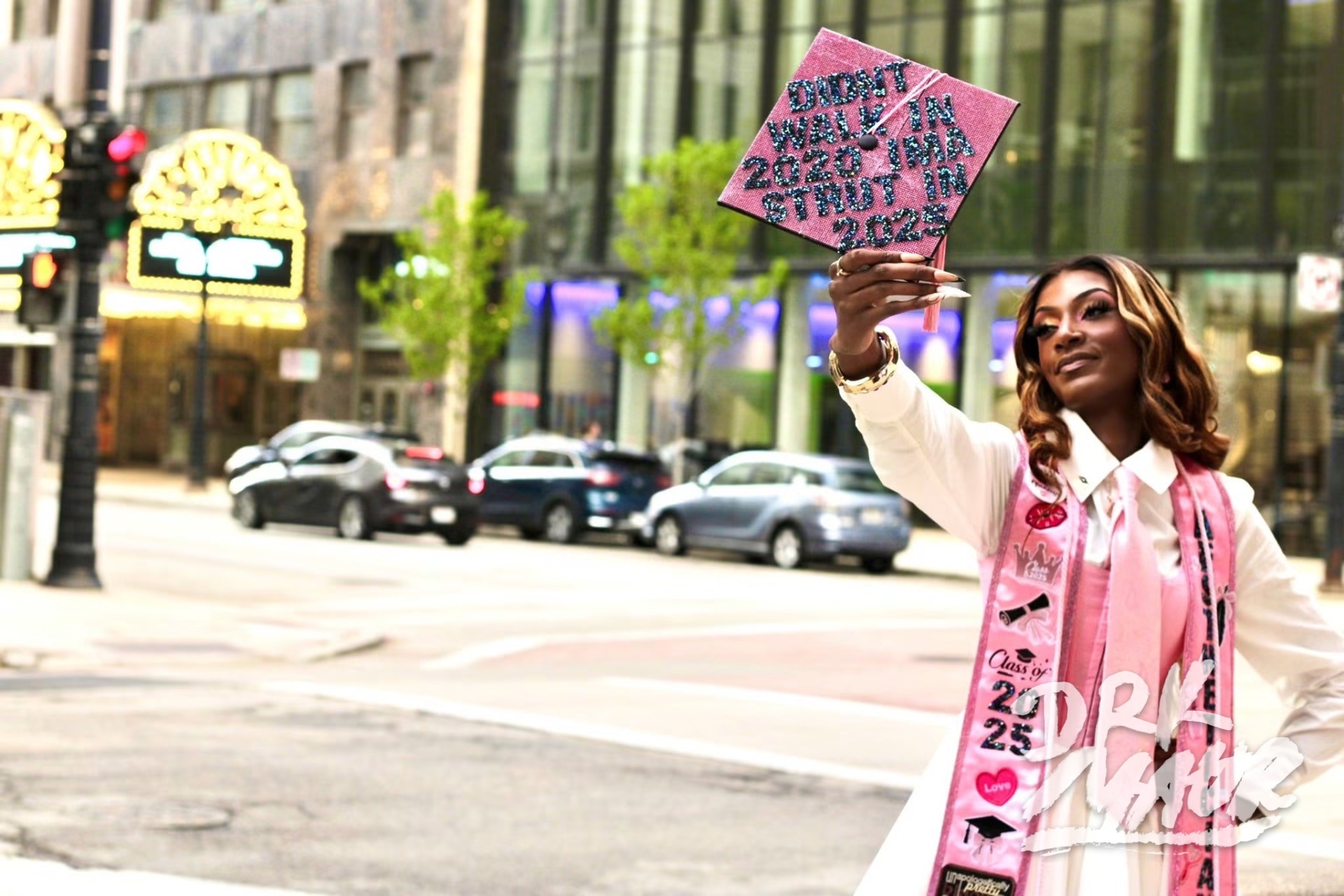 Graduate raising her rhinestone graduation cap above her head on a city street