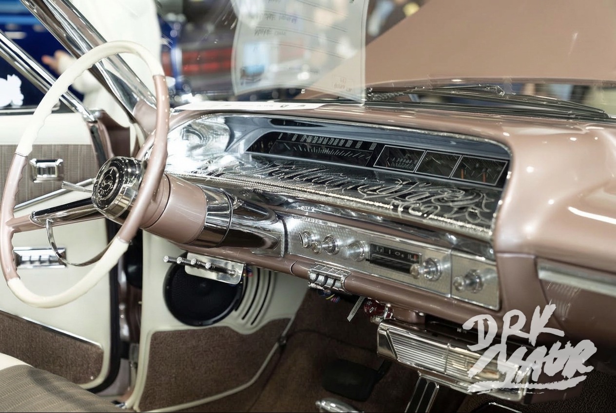 Engraved chrome dashboard and white steering wheel inside a rose gold classic Impala