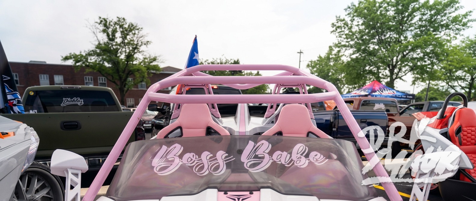 Pink and white Polaris Slingshot with a Boss Babe windshield decal and roll cage