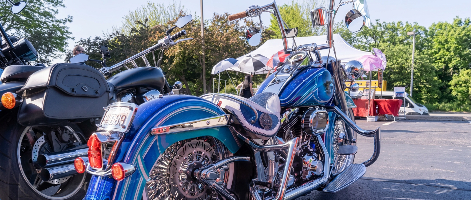 Two custom baggers with ape hanger bars and blue metalflake paint parked side by side at an outdoor bike show