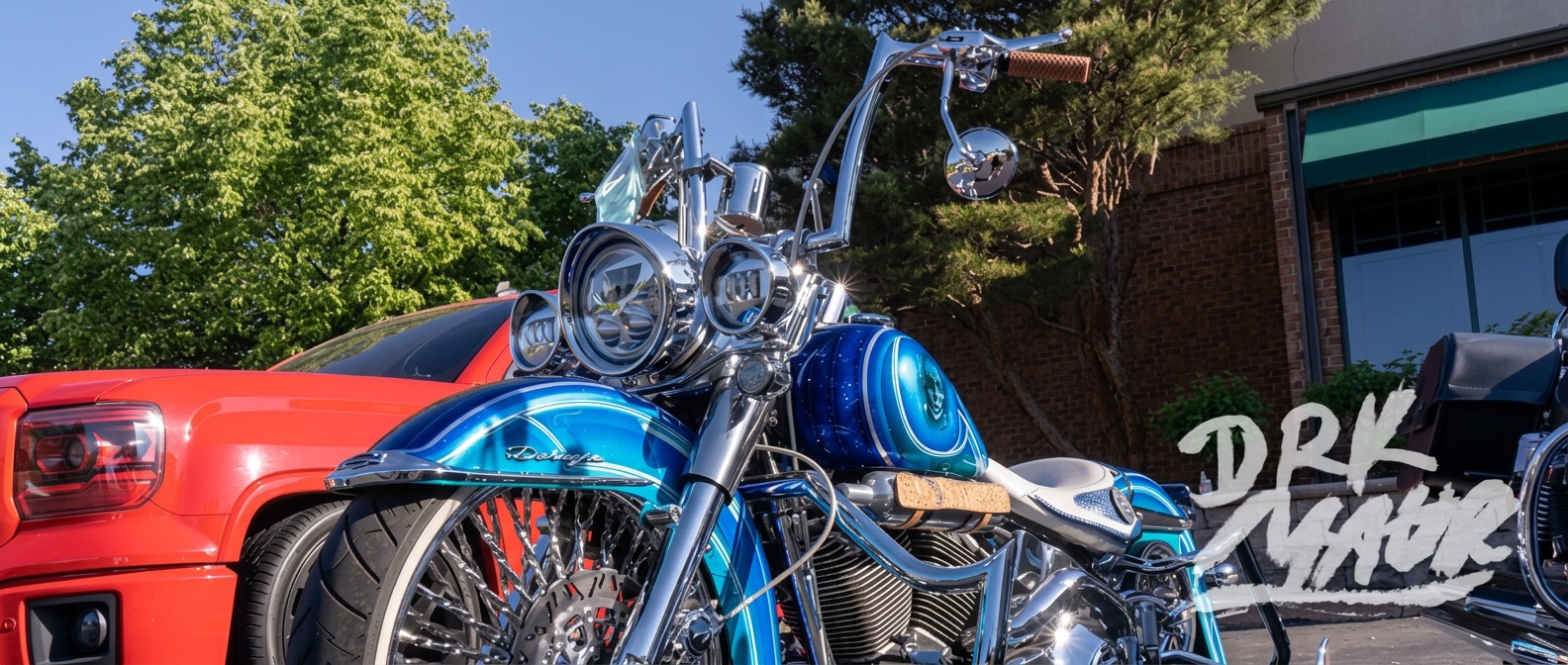 Front view of a blue custom bagger with dual headlights, chrome laced wheel and tall handlebars