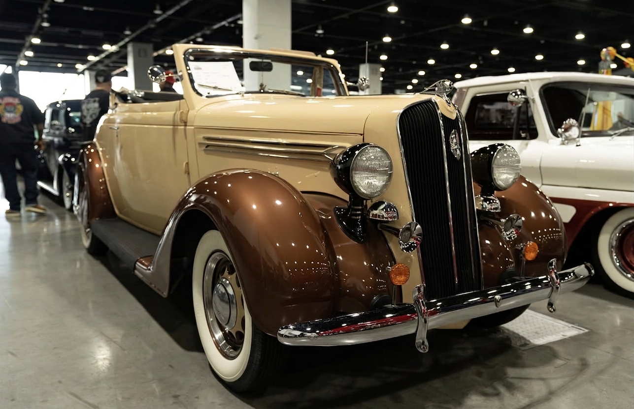 Two-tone cream and brown vintage Plymouth convertible on polished concrete at an indoor car show