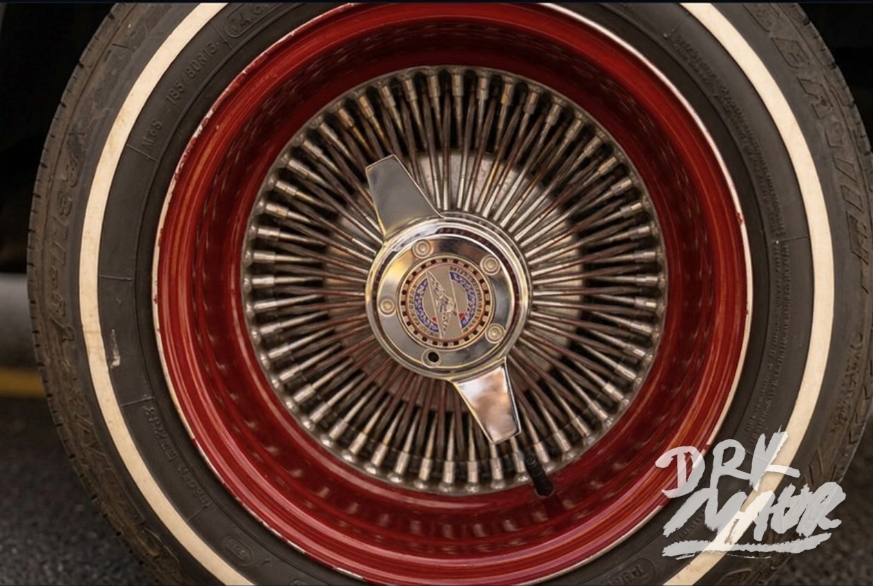 Close-up of a candy red wire spoke wheel with chrome knock-off spinner and whitewall tire